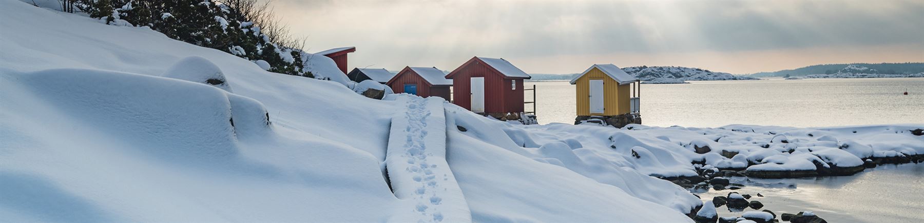 Talvinen rantamaisema ja pikkumökit